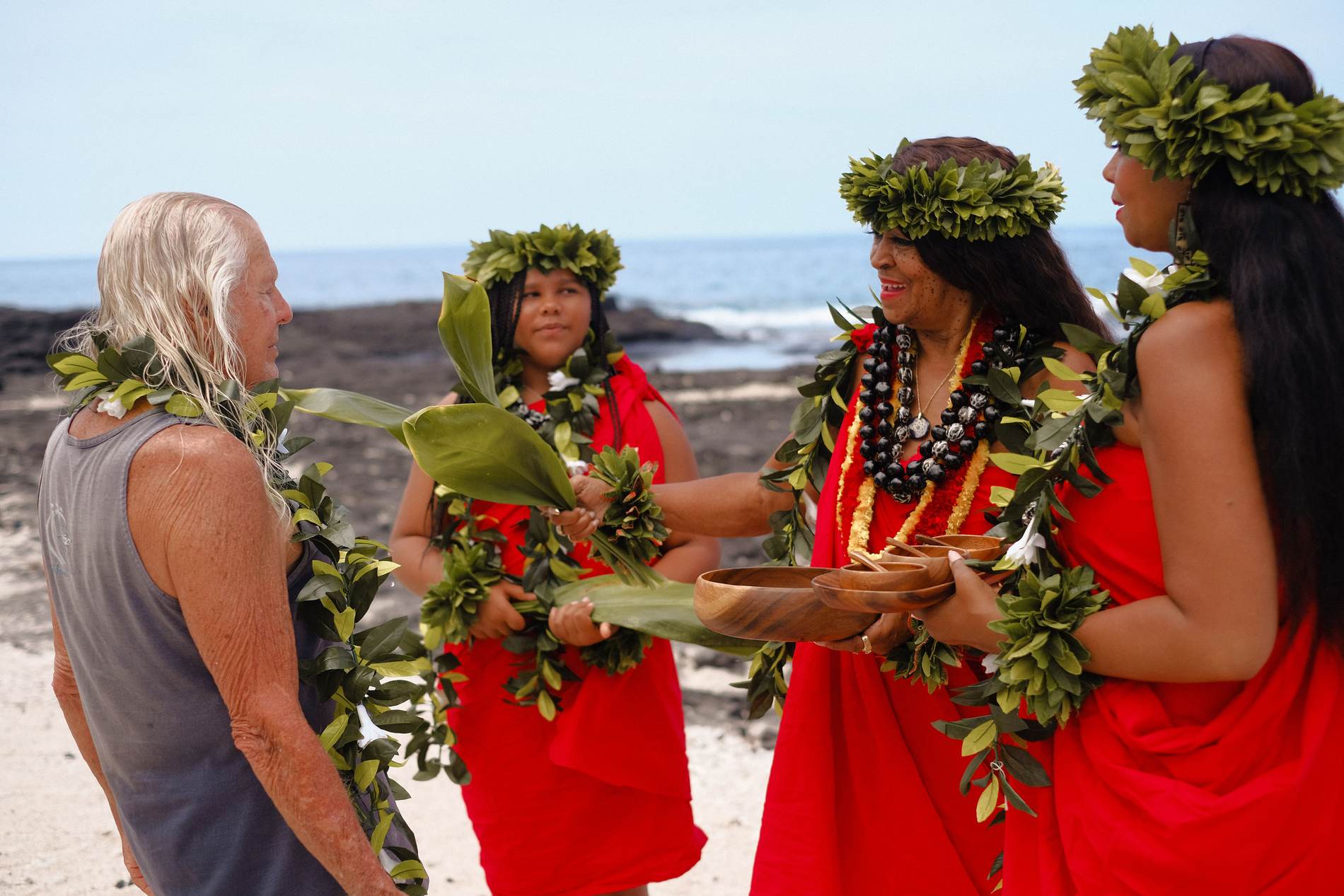 Hands joined over ti leaves in blessing on the shore