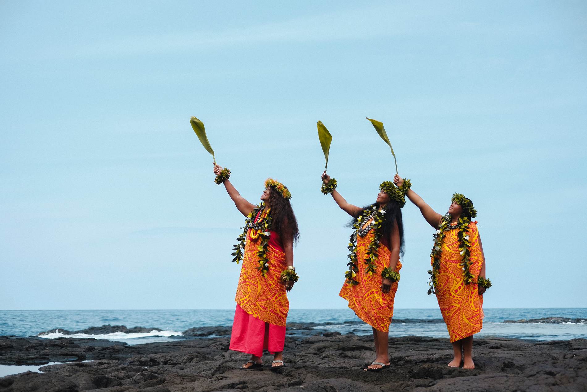 Kahu Kāhealani with her daughter and granddaughter, ti leaves raised to the sea