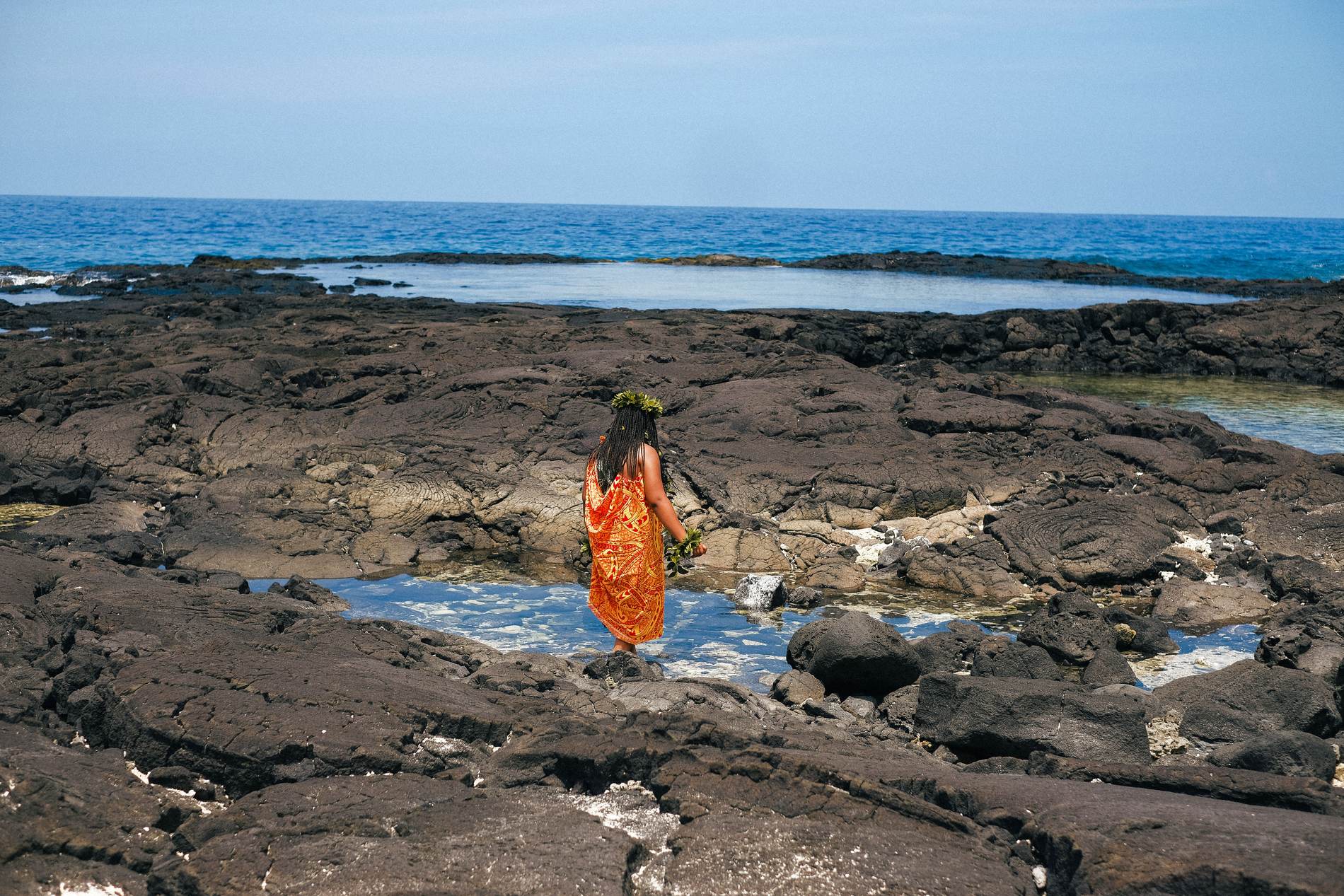 A lone figure walking out across the lava toward the ocean